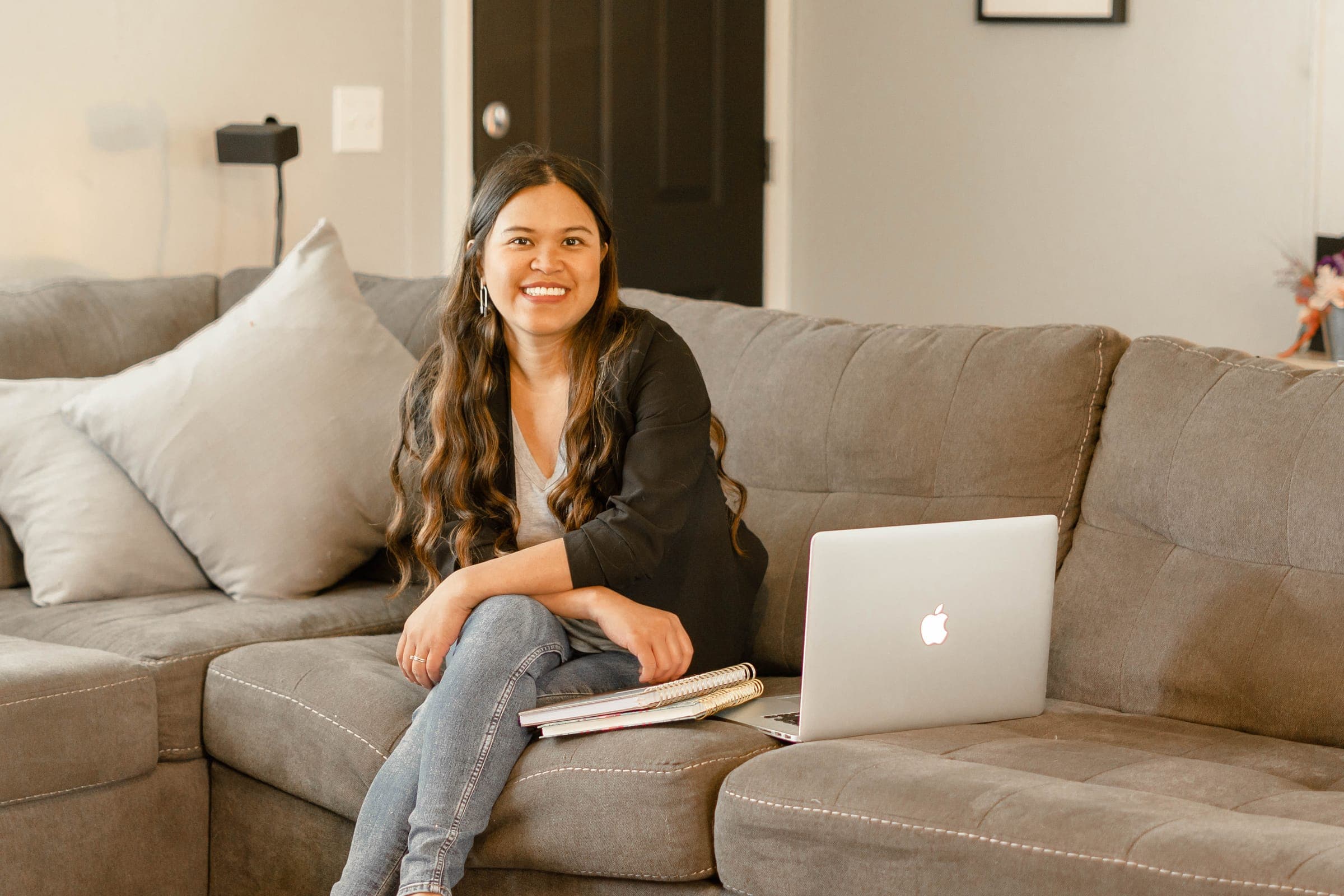 Kristy sitting on a couch with her laptop and planners