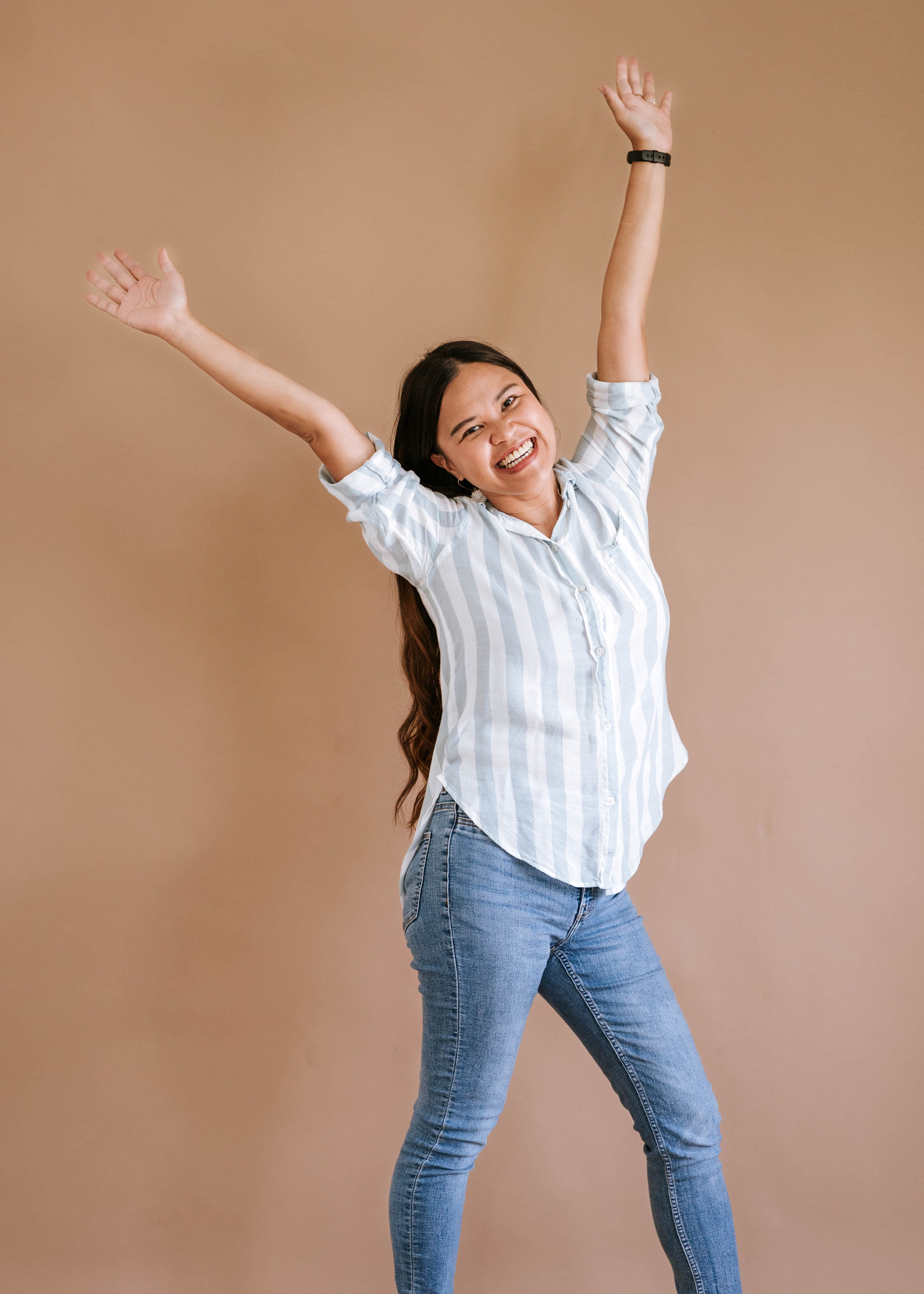 Kristy Yoder, business coach for agency owners, smiling with her arms raised in a celebration of freedom