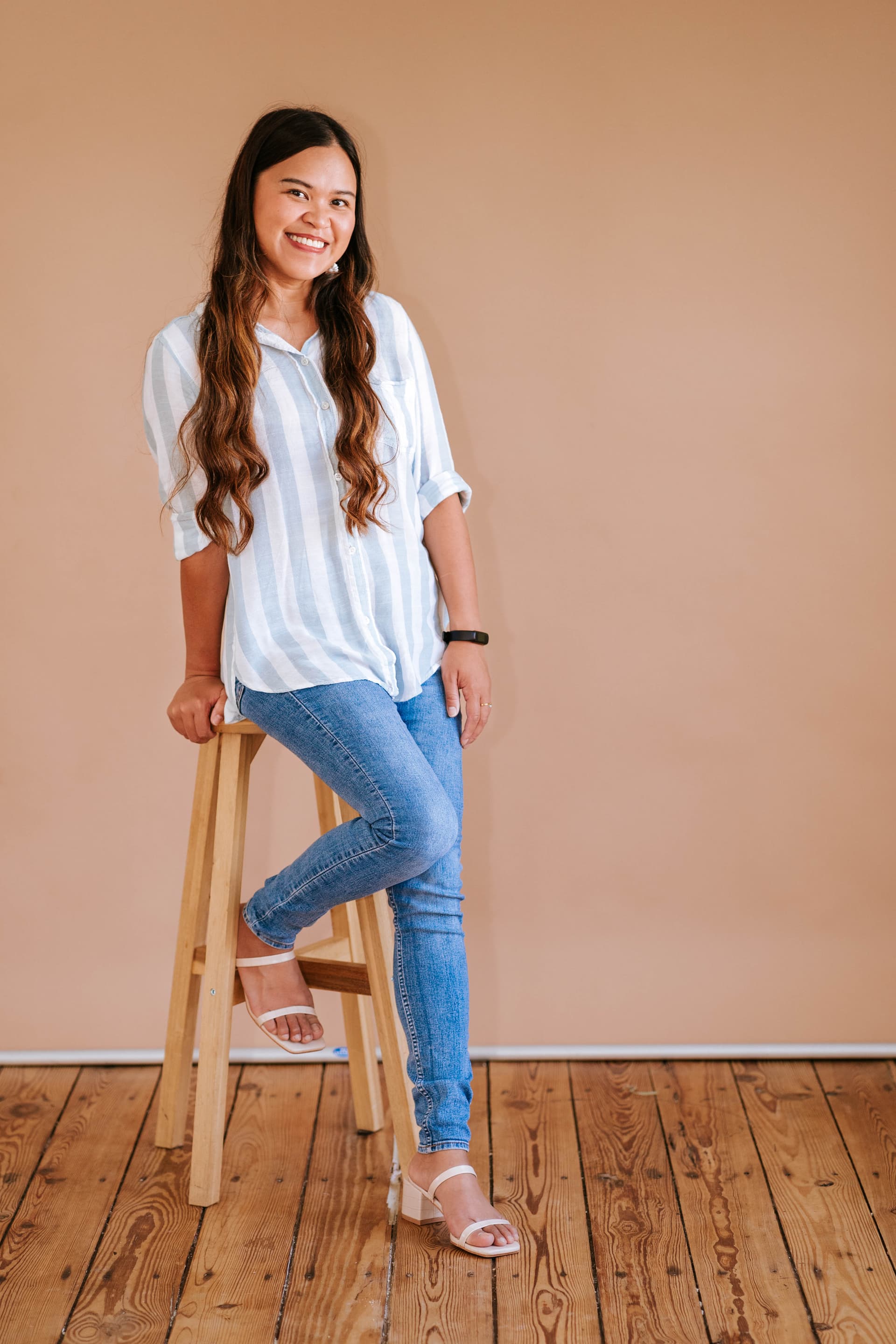 Kristy Yoder smiling, seated on a stool against a warm peach backdrop